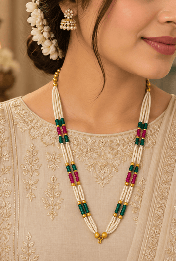 Long multistrand ivory-white pearl-style necklace featuring round gold-tone beads, green and magenta bead sections, and a gold-tone hook clasp, shown from two angles. - bhavmayi