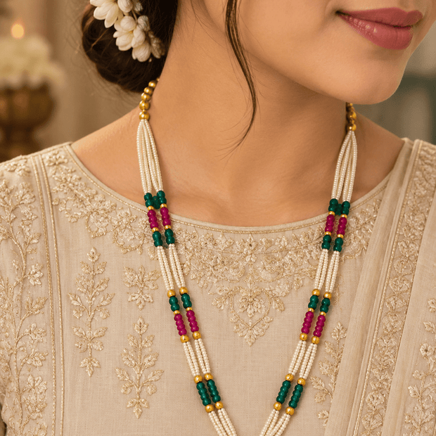 Long multistrand ivory-white pearl-style necklace featuring round gold-tone beads, green and magenta bead sections,- bhavmayi