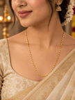 Slender golden chain necklace with repeating small geometric links displayed in a U shape and on a white necklace bust. - bhavmayi